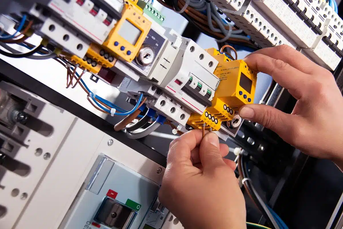 Werkbank mit elektrischen Bauteilen und Lehrling beim Hands-on-Training