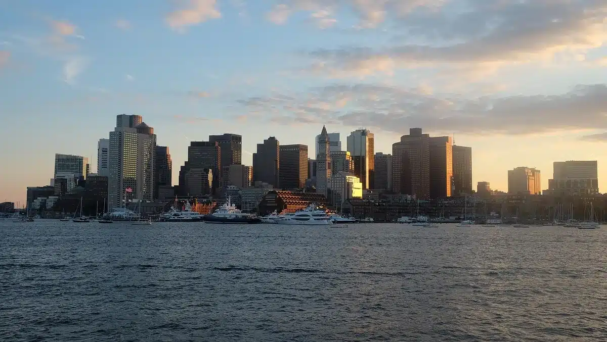 Silhouetten von Fachleuten an einem Konferenztisch mit Laptops vor einem Fenster, Boston im Hintergrund
