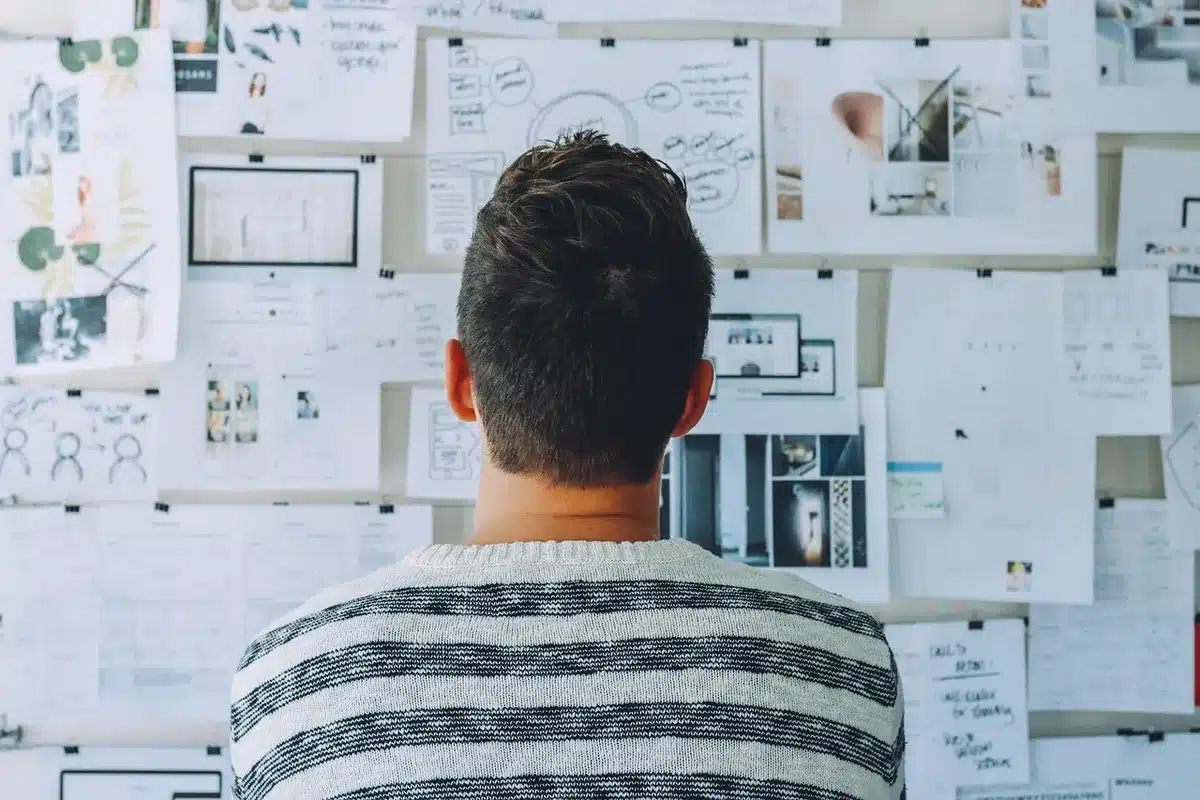 Junge Gründer in einem hellen Co‑Working‑Raum mit Post‑its und Laptops