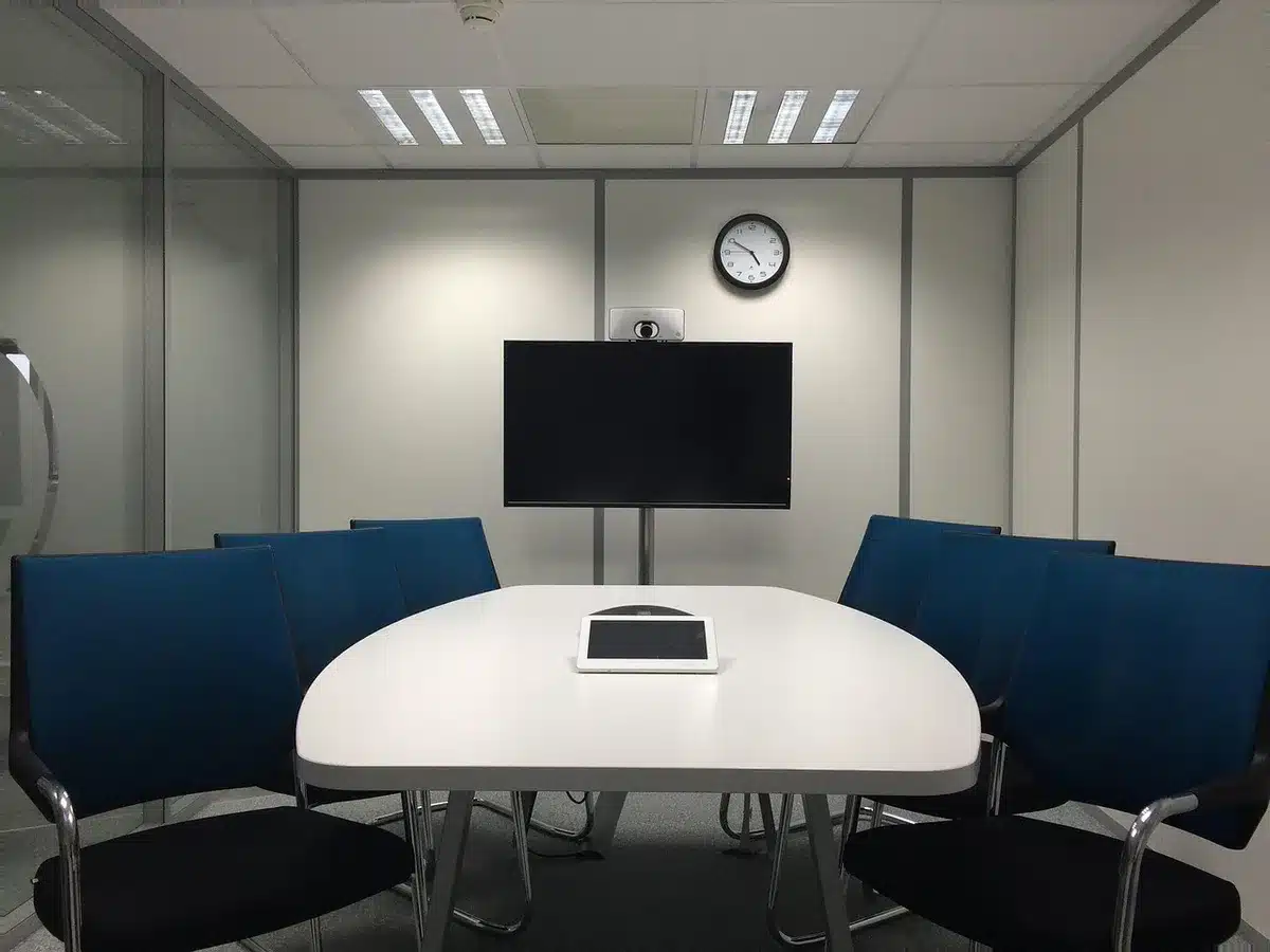 Leerer Konferenzraum mit anonymem Gerät auf dem Tisch und Licht durch Jalousien