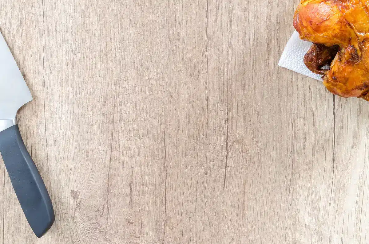 Lehrling schneidet Fleisch unter Anleitung in der Werkstatt