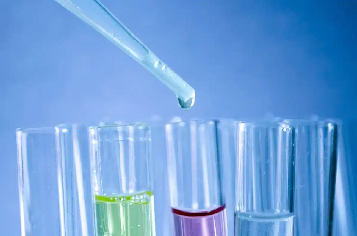 Laborantin am Mikroskop mit Pipette und Proben